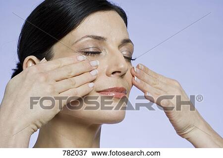 Stock Photo - Portrait of a woman touching her cheeks. Fotosearch