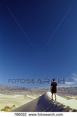 A man standing on a sand dune and looking at view, Death Valley National Park, California, USA View Large Photo Image Stock Image - A man standing on a sand dune and looking at view, Death Valley National Park, California, USA. Fotosearch