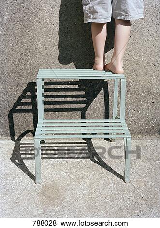Stock Photo - A boy's legs standing on a step ladder, rear view. Fotosearch