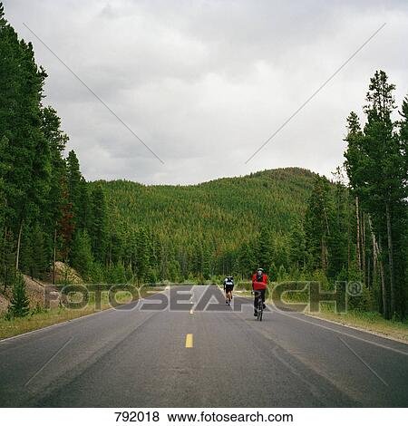 Rear view of two people cycling on a road, Rocky Mountain National Park, Colorado, USA View Large Photo Image Stock Photo - Rear view of two people cycling on a road, Rocky Mountain National Park, Colorado, USA. Fotosearch