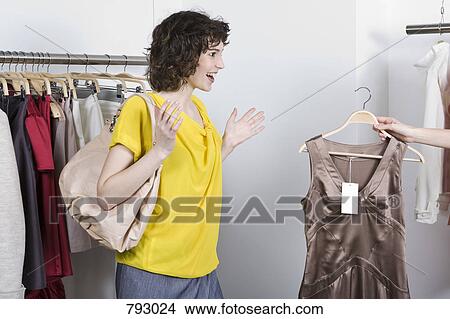 A sales assistance showing a woman a dress in a store View Large Photo Image Picture - A sales assistance showing a woman a dress in a store. Fotosearch
