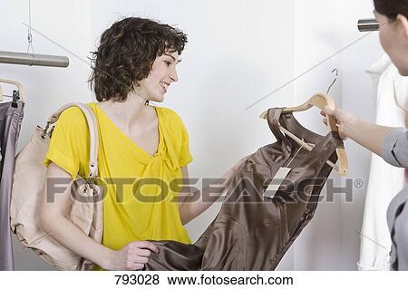 A sales assistant showing a young woman a dress View Large Photo Image Stock Photo - A sales assistant showing a young woman a dress. Fotosearch