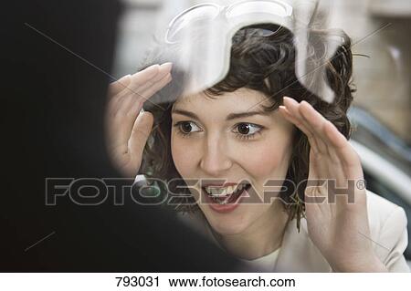 Stock Image - A woman looking excited through a store window. Fotosearch