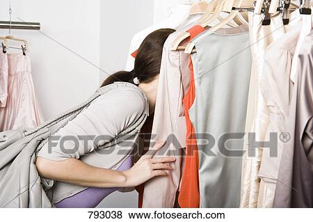 A woman searching through a clothes rail in a store View Large Photo Image Stock Photo - A woman searching through a clothes rail in a store. Fotosearch