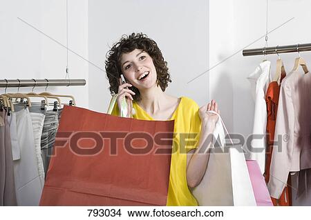 A woman talking on her mobile phone and shopping View Large Photo Image Picture - A woman talking on her mobile phone and shopping. Fotosearch