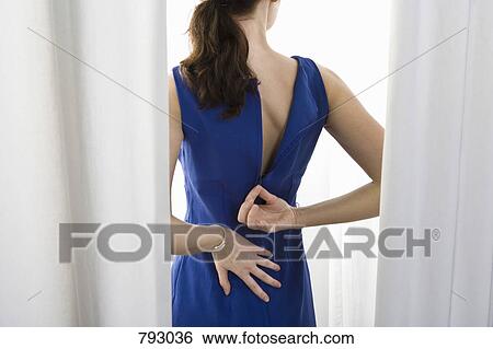 Stock Photograph - A woman trying on a dress. Fotosearch