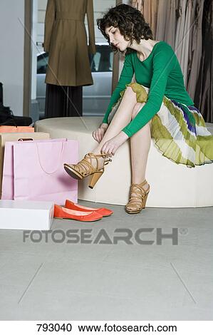A woman trying on shoes in a store View Large Photo Image Stock Image - A woman trying on shoes in a store. Fotosearch