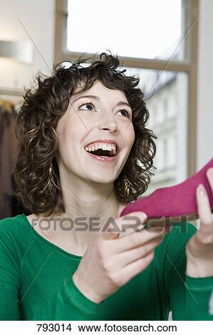 A young woman holding a shoe in a store View Large Photo Image Picture - A young woman holding a shoe in a store. Fotosearch