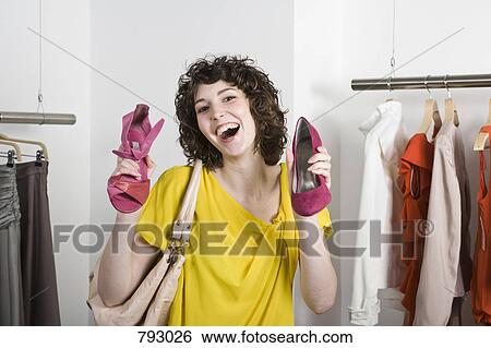 A young woman holding shoes in a store and smiling View Large Photo Image Stock Photograph - A young woman holding shoes in a store and smiling. Fotosearch