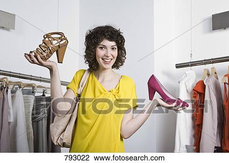 A young woman holding two shoes in a store View Large Photo Image Stock Image - A young woman holding two shoes in a store. Fotosearch