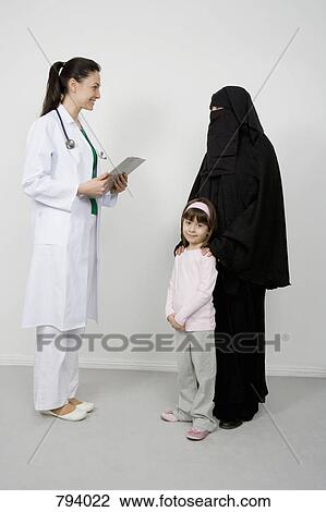 A doctor talking to a woman wearing a Niqaab and her daughter View Large Photo Image Stock Image - A doctor talking to a woman wearing a Niqaab and her daughter. Fotosearch