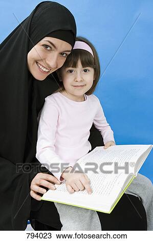 A mother wearing a Hijab and her daughter reading a book View Large Photo Image Stock Image - A mother wearing a Hijab and her daughter reading a book. Fotosearch