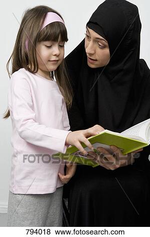 A mother wearing a Hijab and her daughter reading a book View Large Photo Image Stock Photo - A mother wearing a Hijab and her daughter reading a book. Fotosearch