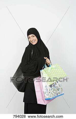 A woman wearing a Hijab and holding shopping bags View Large Photo Image Stock Photo - A woman wearing a Hijab and holding shopping bags. Fotosearch