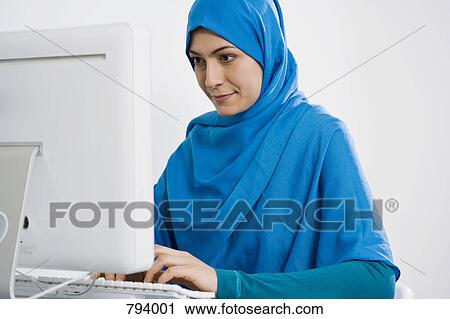 A woman wearing a Hijab using a computer View Large Photo Image Stock Image - A woman wearing a Hijab using a computer. Fotosearch