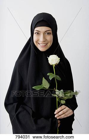 Portrait of a woman wearing a Hijab and holding a rose View Large Photo Image Stock Image - Portrait of a woman wearing a Hijab and holding a rose. Fotosearch