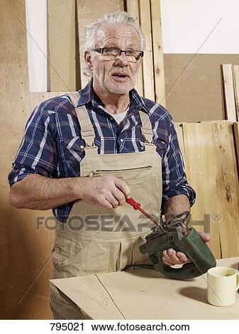 A man adjusting a power jigsaw View Large Photo Image Stock Image - A man adjusting a power jigsaw. Fotosearch