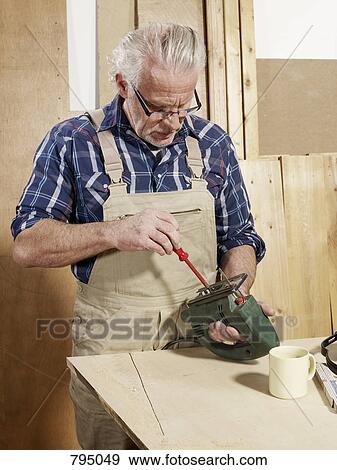A man adjusting a power jigsaw View Large Photo Image Stock Photo - A man adjusting a power jigsaw. Fotosearch