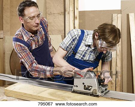 A man assisting a young man sawing wood View Large Photo Image Stock Photo - A man assisting a young man sawing wood. Fotosearch
