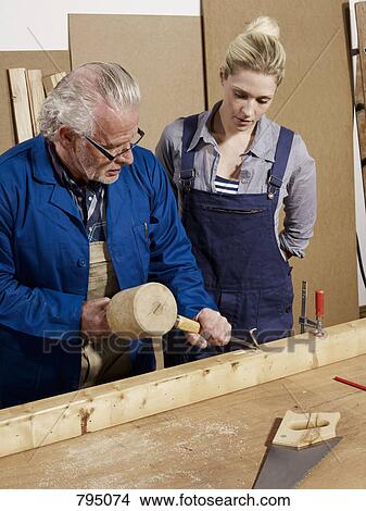 A man demonstrating wood chiseling to a woman in a workshop View Large Photo Image Picture - A man demonstrating wood chiseling to a woman in a workshop. Fotosearch