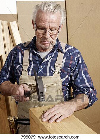 A man hammering nails into wood View Large Photo Image Stock Photo - A man hammering nails into wood. Fotosearch