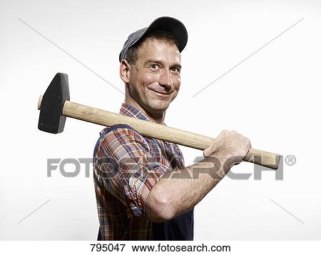 A man holding a sledgehammer over his shoulder View Large Photo Image Stock Photo - A man holding a sledgehammer over his shoulder. Fotosearch