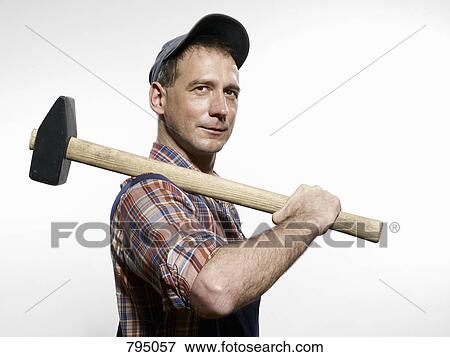 A man holding a sledgehammer over his shoulder View Large Photo Image Stock Photo - A man holding a sledgehammer over his shoulder. Fotosearch
