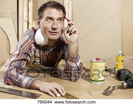 A man leaning on a workbench and thinking View Large Photo Image Picture - A man leaning on a workbench and thinking. Fotosearch