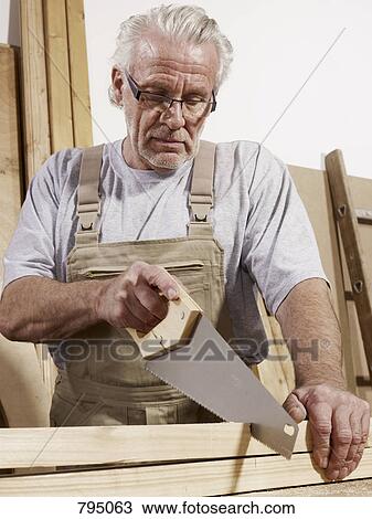 A man sawing wood View Large Photo Image Stock Image - A man sawing wood. Fotosearch