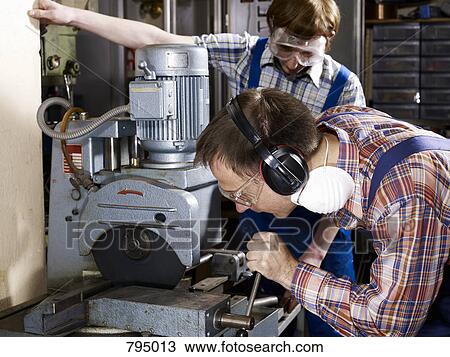 A man using a electric saw in a workshop while a young man looks on View Large Photo Image Stock Image - A man using a electric saw in a workshop while a young man looks on. Fotosearch
