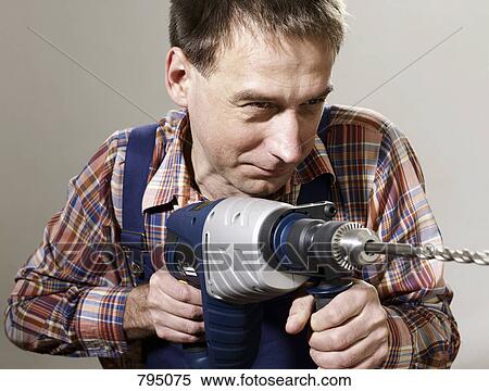 Stock Photography - A man using a large drill. Fotosearch