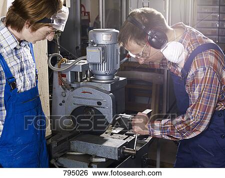 A man using an electric saw in a workshop while a young man looks on View Large Photo Image Stock Photograph - A man using an electric saw in a workshop while a young man looks on. Fotosearch