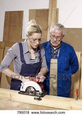 A man watching a woman sawing wood View Large Photo Image Stock Photo - A man watching a woman sawing wood. Fotosearch