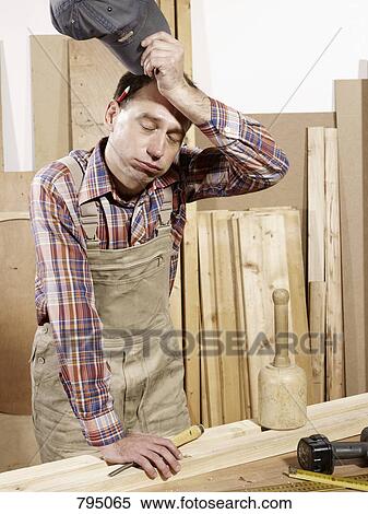 A man wiping his brow in a wood workshop View Large Photo Image Stock Photography - A man wiping his brow in a wood workshop. Fotosearch