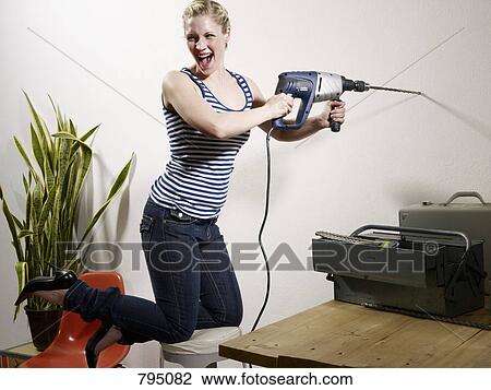 A woman drilling into a wall View Large Photo Image Stock Image - A woman drilling into a wall. Fotosearch