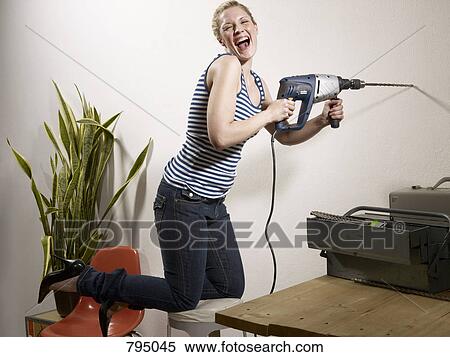 Stock Photography - A woman drilling into a wall. Fotosearch