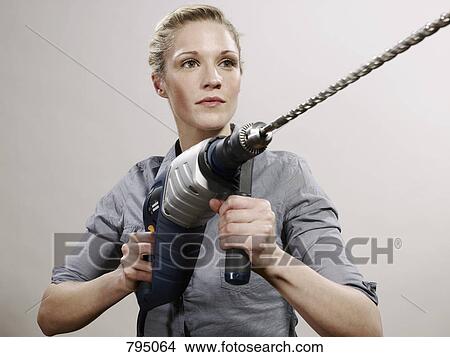 A woman holding a large drill View Large Photo Image Picture - A woman holding a large drill. Fotosearch