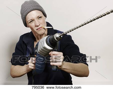 A woman holding a large drill View Large Photo Image Stock Photograph - A woman holding a large drill. Fotosearch