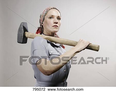 A woman holding a sledgehammer over her shoulder View Large Photo Image Stock Image - A woman holding a sledgehammer over her shoulder. Fotosearch