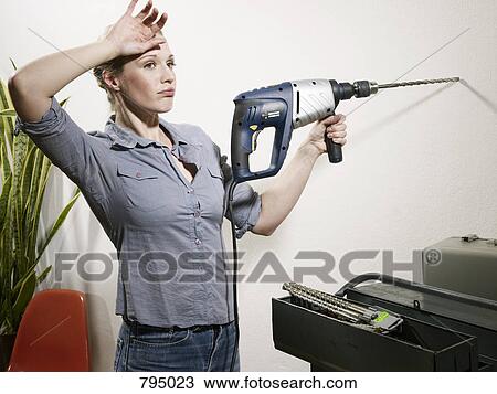 A woman resting from drilling into a wall View Large Photo Image Stock Image - A woman resting from drilling into a wall. Fotosearch