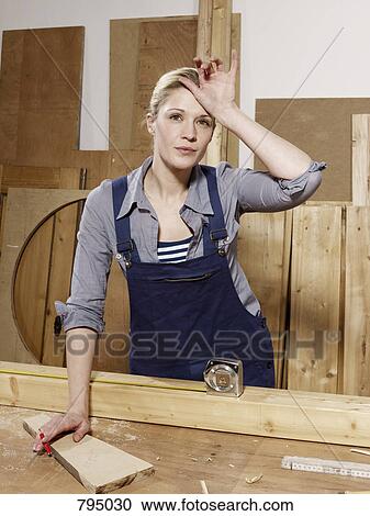 A woman wiping her brow in a wood workshop View Large Photo Image Stock Image - A woman wiping her brow in a wood workshop. Fotosearch