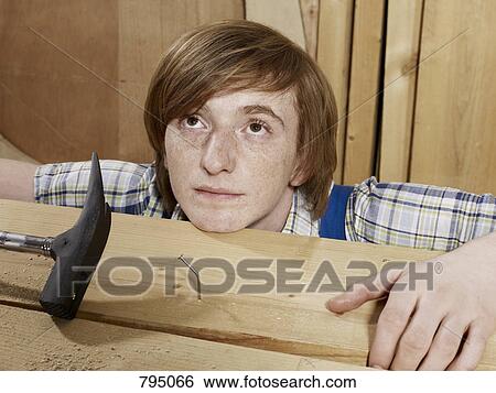 A young man behind a bent nail in wood View Large Photo Image Stock Photograph - A young man behind a bent nail in wood . Fotosearch