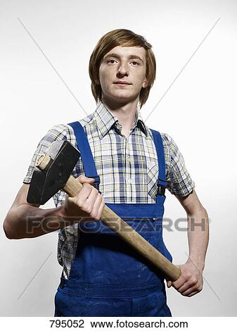 A young man holding a sledgehammer View Large Photo Image Stock Image - A young man holding a sledgehammer. Fotosearch