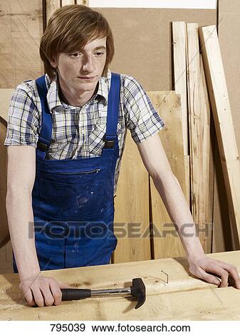 A young man leaning on a bench in a wood workshop View Large Photo Image Stock Photo - A young man leaning on a bench in a wood workshop. Fotosearch