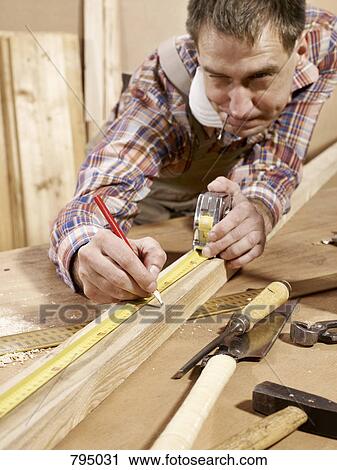 Man marking piece of timber using pencil and tape measure View Large Photo Image Stock Image - Man marking piece of timber using pencil and tape measure. Fotosearch