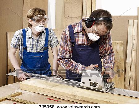 Two men cutting wood in a workshop View Large Photo Image Stock Photograph - Two men cutting wood in a workshop. Fotosearch