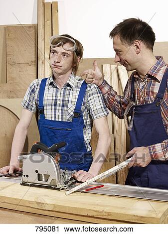 Two men standing at a workbench View Large Photo Image Stock Image - Two men standing at a workbench. Fotosearch