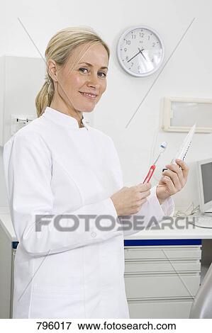 Stock Photo - A dental assistant holding a toothbrush and toothpaste. Fotosearch
