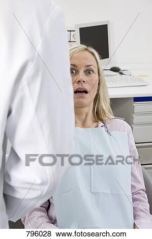 Stock Photo - An anxious patient sitting in a dentist's chair. Fotosearch