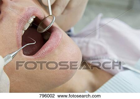Close-up of a dentist inspecting a woman's mouth View Large Photo Image Stock Image - Close-up of a dentist inspecting a woman's mouth. Fotosearch